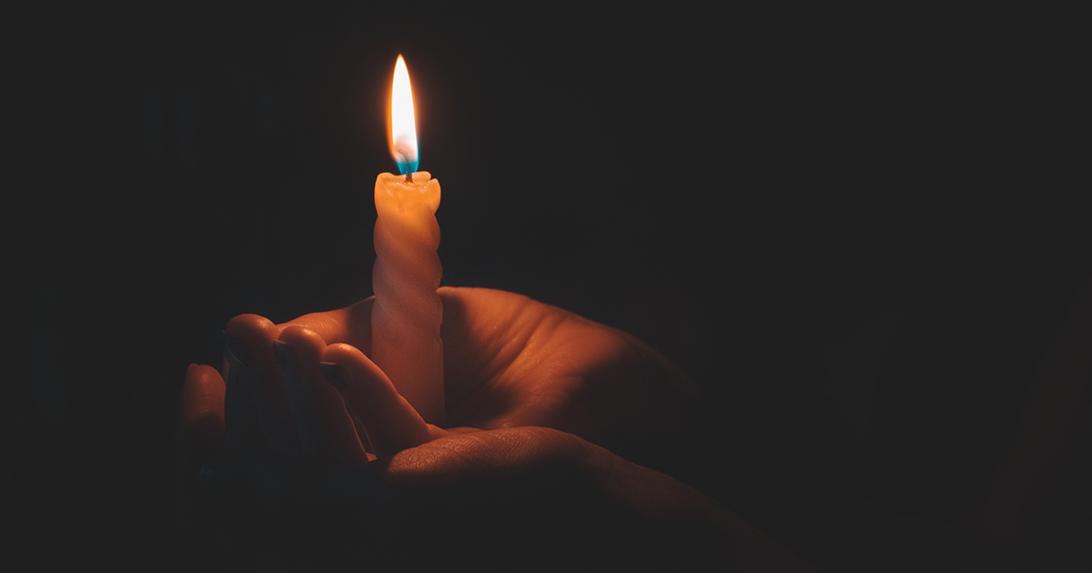 Hand in the dark holding a candle