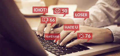 Person at keyboard with digital text bubbles showing cyberbullying words
