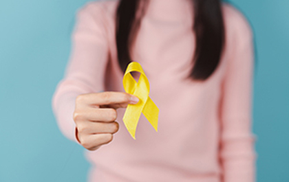 picture of middle section of female in pink top holding yellow ribbon bow